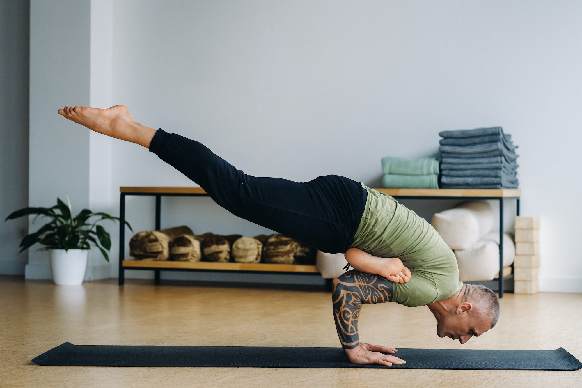 A male athlete in a green T-shirt Does Yoga in the gym
