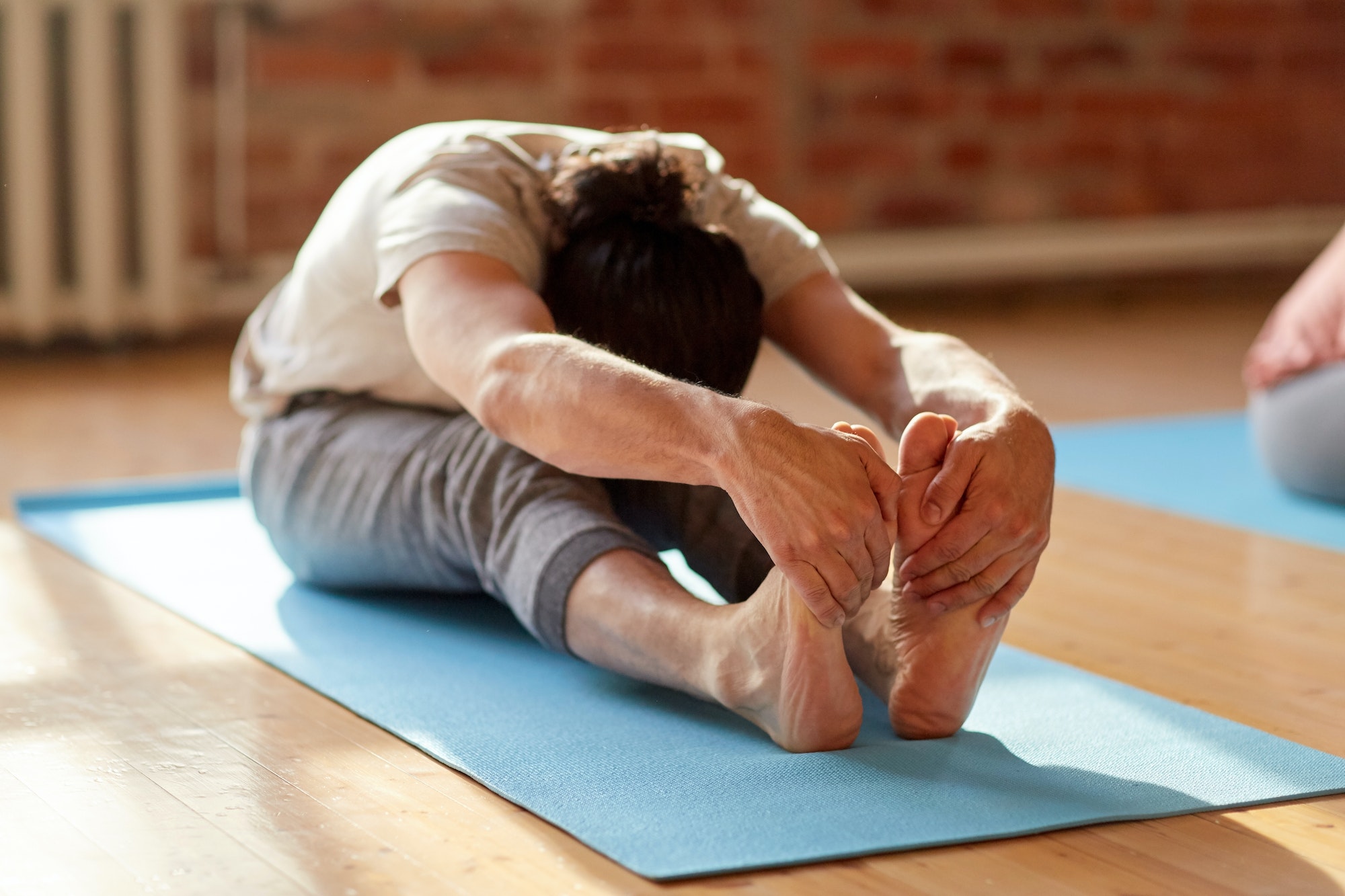 man doing yoga forward bend at studio or gym